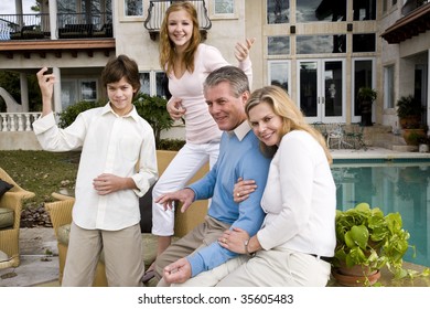 Portrait Of Carefree Family, Kids Playing Air Guitar On Patio