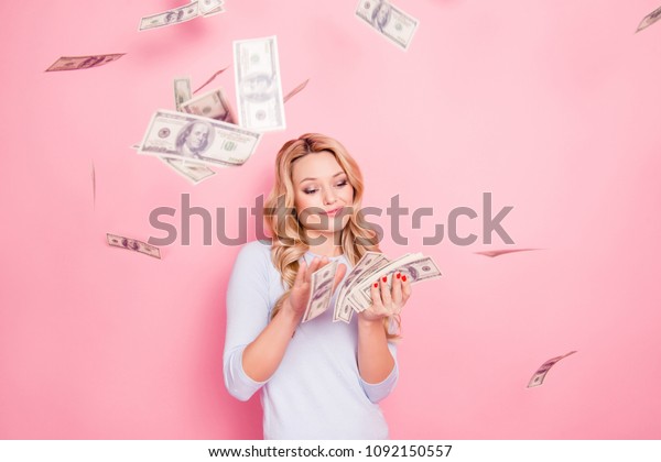 Portrait of carefree girlfriend, student\
wasting stack of much money, winner in casino lottery, having a lot\
of hundred dollars isolated on pink\
background