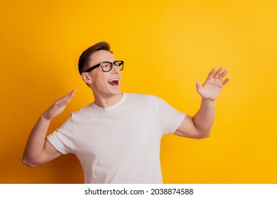 Portrait Of Carefree Relaxed Charming Guy Look Empty Space Dance Raise Hands On Yellow Background