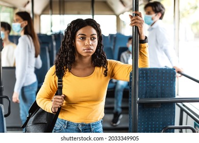 Portrait of careless African American woman standing inside public transport without mask, holding handle ignores warning and health advice about covid, risks spreading the infectious disease