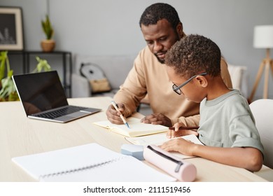 Portrait of caring father helping son with homework while studying at home, copy space - Powered by Shutterstock