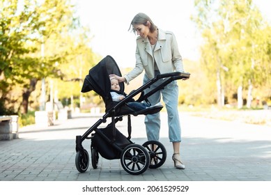 Portrait of a caring mother with her little daughter in stroller in park