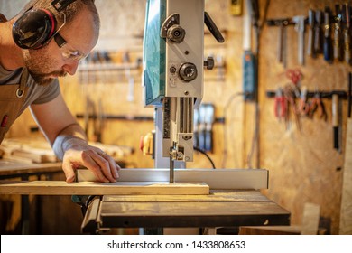 portrait of a carpenter inside his carpentry workshop using a band saw. Wear ear and eye protection - Powered by Shutterstock