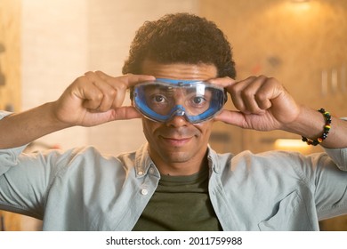 Portrait Of A Carpenter Putting On Safety Goggles Over His Head In His Workshop.