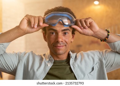 Portrait Of A Carpenter Putting On Safety Goggles Over His Head In His Workshop.