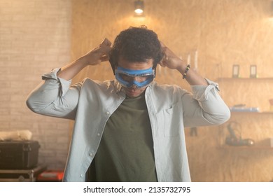 Portrait Of A Carpenter Putting On Safety Goggles Over His Head In His Workshop.