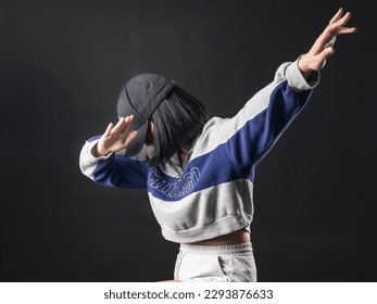 A portrait of a casual fashion-style Asian (Chinese Indonesian) Girl posing dan dancing with a Hip hop style. Isolated on a black background