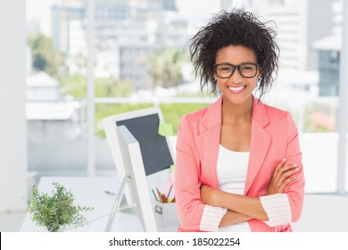 Portrait of a casual female artist standing with arms crossed at a bright office - Powered by Shutterstock