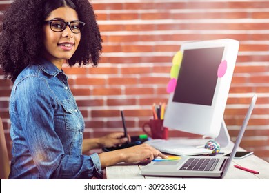 Portrait of casual female designer smiling and working at workplace