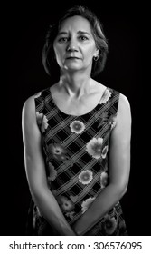 Portrait of a casual middle aged woman isolated over black background. Black & White picture.