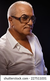 Portrait Of Casual Old Man In White Shirt And Glasses Over Black Background. Side View.