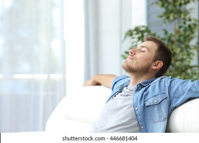 Portrait of a casual tired man resting sitting on a couch at home