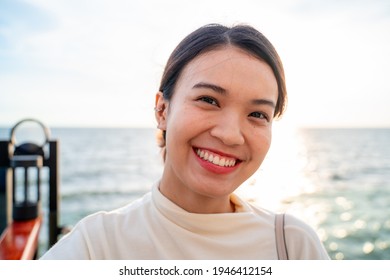 Portrait Of A Casually White Dressed, Young Asian Woman Smiling, Authentic People, Standing Alone Outside On Summer Beach, Looking Camera, Smiling Friendly, Candid, Sunset.