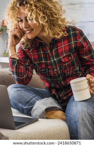 Portrait of caucasian adult beautiful woman at home use a laptop computer sitting on the couch - concept of video call conference and smart work - people and connection - watching movie