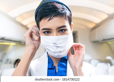 Portrait Of Caucasian Beautiful Air Hostess Or Flight Attendant Wearing Medical Protective Mask To Prevent Coronavirus Or Covid19 At The Airline Airplane. Airport Rule For Safe Traveling, New Normal 