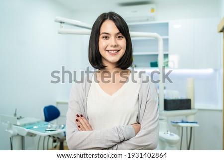 Portrait of Caucasian beautiful girl patient standing infront of dental clinic, preparing for treatment from professional dentist for oral care check up. Young woman is smilling and looking at camera.