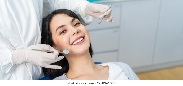 Portrait of Caucasian beautiful young girl patient toothy smile while receiving treatment from dentist doctor for oral check up and examining cavities and gum disease for tooth care at dental clinic.
