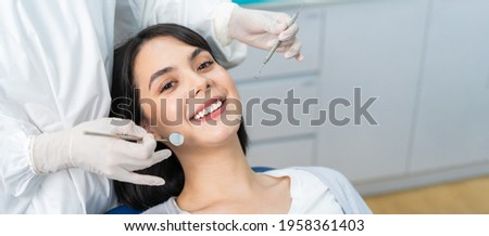 Portrait of Caucasian beautiful young girl patient toothy smile while receiving treatment from dentist doctor for oral check up and examining cavities and gum disease for tooth care at dental clinic.