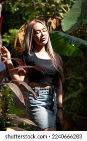 portrait of caucasian beauty girl ashen hair wear black t shirt and jean skirt standing in garden in high contrast day light - Shutterstock ID 2240666283