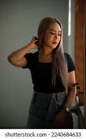 portrait of caucasian beauty girl ashen hair wear black t shirt and jean skirt standing with window light - Shutterstock ID 2240684633