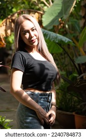 portrait of caucasian beauty girl ashen hair wear black t shirt and jean skirt standing in garden in high contrast day light - Shutterstock ID 2240784873