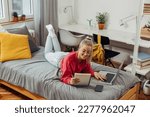 portrait of caucasian blonde female laying on bed and using laptop in in dorm room