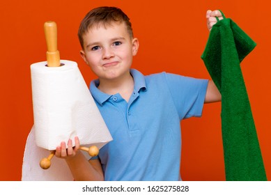 Portrait Of A Caucasian Boy. The Boy Holds A Paper Towel, The Other Hand Used To Towel. Which Is Better. Housewives Concept.