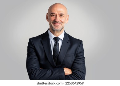 Portrait of caucasian business man looking at camera and smiling. Confident mature male professional is in suit. He is against gray background. - Powered by Shutterstock