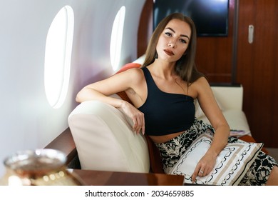 Portrait Of Caucasian Business Woman Passenger On An Airplane, Aboard Private Jet. Young Girl Travels By Plane. Travel Concept