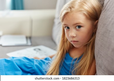 portrait of caucasian child girl in dress sitting on sofa in living , beautiful kid girl is sad. mom and dad drawing in the background as a symbol of divorce close up sad portrait - Shutterstock ID 1823686313