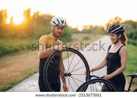 Portrait of a caucasian couple fixing a broken wheel while riding a bike outside. Man and woman changing broken tire on a bike. Concept of healthy lifestyle and outdoor sport. Copy space.