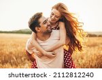 Portrait of a caucasian couple man carrying on back redhead lover anjoying sunlight weekend vacation holidays concept