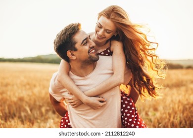 Portrait of a caucasian couple man carrying on back redhead lover anjoying sunlight weekend vacation holidays concept