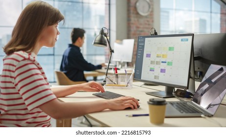 Portrait of Caucasian Creative Young Woman Working on a Calender Software on a Desktop Computer in Bright Busy Office. Female Team Lead Smiling Happily While Checking Team Events for the Month. - Shutterstock ID 2216815793