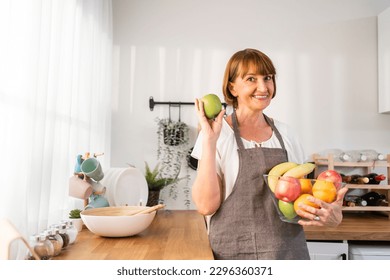 Portrait of Caucasian elderly woman hold fruit bowl and look at camera. Senior older mature female spend free leisure time enjoy eat clean vegetables for health in house. Diet and Healthy food concept - Powered by Shutterstock