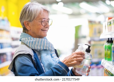 Portrait Of Caucasian Elderly Woman Making Purchase In Supermarket, Elderly Smiling Lady Selecting And Checking Prices Of Hand Liquid Soap