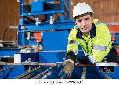 Portrait caucasian engineer checking machine at metal sheet factory	
