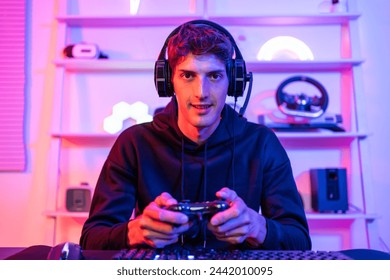 Portrait of Caucasian e-sport male gamer play video game on computer. Handsome man gaming player feel happy and excited, enjoy technology broadcast live streaming while plays cyber tournament at home. - Powered by Shutterstock