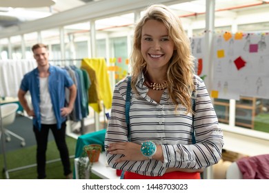 Portrait of Caucasian female fashion designer standing with arms crossed in design studio. Caucasian man standing in that background. This is a casual creative start-up business office for a diverse - Powered by Shutterstock