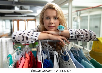 Portrait of Caucasian female fashion designer leaning on clothes rack in design studio. This is a casual creative start-up business office for a diverse team - Powered by Shutterstock