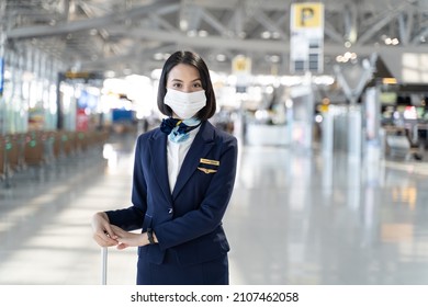 Portrait Of Caucasian Flight Attendant Standing In Airport Terminal. Attractive Beautiful Cabin Crew Or Air Hostess Woman Wearing Face Mask Prepare To Work In Airplane During Covid19 Pandemic Crisis.