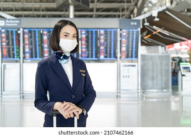 Portrait Of Caucasian Flight Attendant Standing In Airport Terminal. Attractive Beautiful Cabin Crew Or Air Hostess Woman Wearing Face Mask Prepare To Work In Airplane During Covid19 Pandemic Crisis.