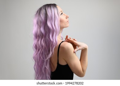 Portrait Of A Caucasian Girl With Long Purple Hair Posing At The Camera With A Wig On A White Background