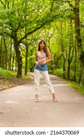 Portrait Of A Caucasian Girl On A Path In A City Park, Fashionably Posed In Nature