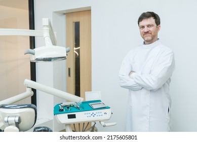 Portrait Of Caucasian Male Dentist Stand Cross Arm In Dental Exam Room. Handsome Young Man Dental Doctor Standing With Confident In Dental Examination Room, Smiling And Looking At Camera At Clinic.