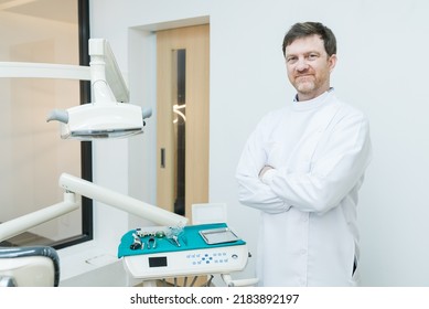 Portrait Of Caucasian Male Dentist Stand Cross Arm In Dental Exam Room. Handsome Young Man Dental Doctor Standing With Confident In Dental Examination Room, Smiling And Looking At Camera At Clinic.