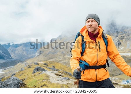 Portrait of caucasian man with backpack and trekking poles in Makalu Barun Park route near Khare. Mera peak climbing acclimatization active walk. Backpacker enjoying valley view. Active people concept