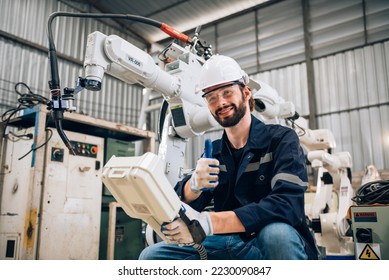 Portrait of caucasian man specialist engineer in uniform smiling and showing thumb up and holding robotic arm controller for working in smart industrial factory. - Powered by Shutterstock - Get 15% off with code: PIKWIZARD15
