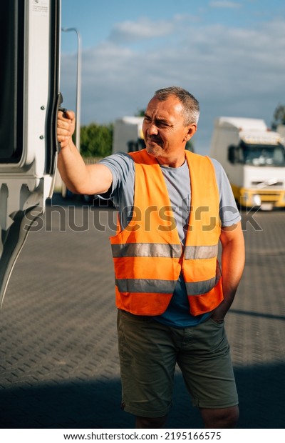 Portrait of caucasian mature man on\
semi-truck vehicles parking background. Truck driver worker\
