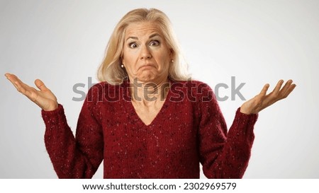 Portrait of caucasian mature woman in casual outfit shrugging, and throwing up hands with helplessness, over white background. Concept of emotions